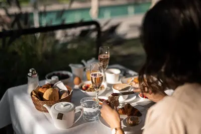 a woman sitting at a table with food and glasses of wine at Hotel Pollinger in Merano