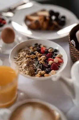 a table topped with a bowl of cereal and fruit at Hotel Pollinger in Merano