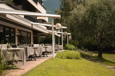 a restaurant with white tables and chairs in front of a building at Hotel Pollinger in Merano
