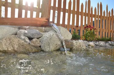 a water fountain in front of a fence at Naturchalet in San Vigilio Di Marebbe