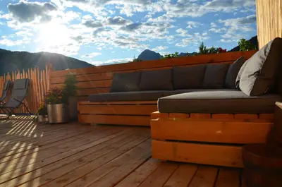 a couch on a deck with a view of the mountains at Naturchalet in San Vigilio Di Marebbe