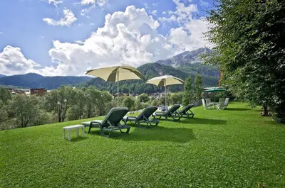 a row of chairs and umbrellas on a lawn at Mountain B&B - La Scalira in Corvara in Badia