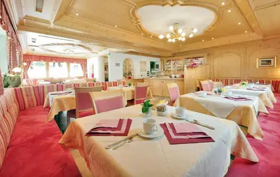 a restaurant with white tables and pink chairs at Mountain B&B - La Scalira in Corvara in Badia