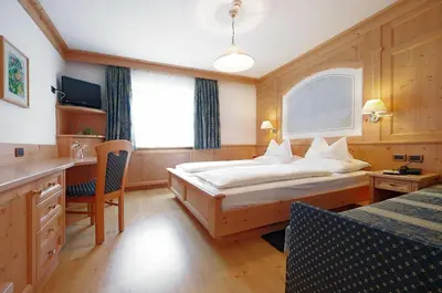 a bedroom with a bed and a desk and a window at Mountain B&B - La Scalira in Corvara in Badia