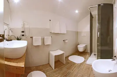 a white bathroom with a sink and a toilet at Mountain B&B - La Scalira in Corvara in Badia