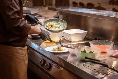 a person preparing food in a restaurant kitchen at Veronza Clubresidence in Cavalese