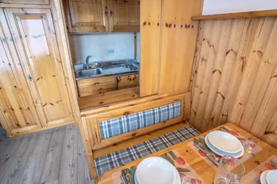 a kitchen with wooden cabinets and a table and a sink at Veronza Clubresidence in Cavalese