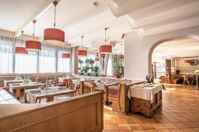a restaurant with tables and chairs and windows at Veronza Clubresidence in Cavalese