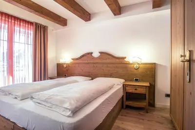 a bedroom with a large bed and a wooden headboard at Al Sole Clubresidence in Canazei