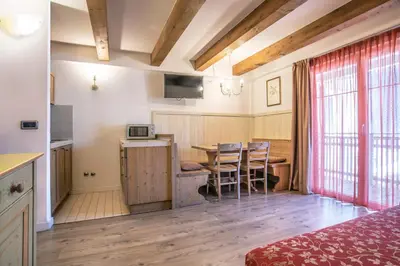 a room with a kitchen and a table with chairs at Al Sole Clubresidence in Canazei