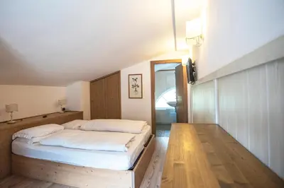 a bedroom with a bed with white sheets on it at Al Sole Clubresidence in Canazei