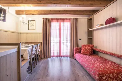 a living room with a red couch and a table at Al Sole Clubresidence in Canazei