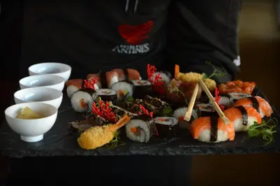 a man holding a tray of sushi and other foods at Hotel Antines in La Villa