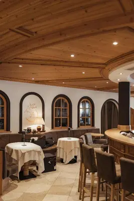 a restaurant with tables and chairs and wooden ceilings at Hotel Antines in La Villa