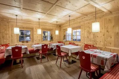 a restaurant with wooden walls and tables and red chairs at Albergo Posta Pederoa in La Valle