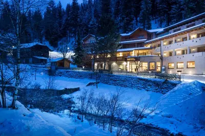 a large building in the snow at night at Albergo Posta Pederoa in La Valle