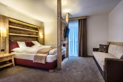 a hotel room with a bunk bed and a couch at Albergo Posta Pederoa in La Valle