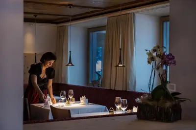 a woman standing at a table in front of a mirror at Albergo Posta Pederoa in La Valle