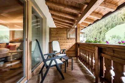 a room with two chairs and a table on a balcony at Albergo Posta Pederoa in La Valle