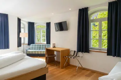 a hotel room with a bed and a desk and window at Hotel Sachsenklemme in Fortezza