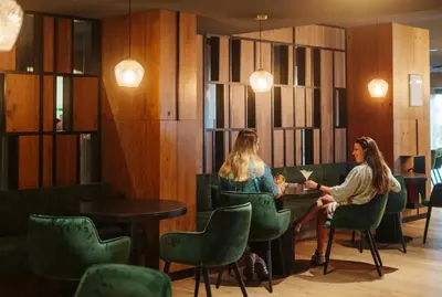 two women sitting at a table in a restaurant at Hotel Antares in Selva di Val Gardena