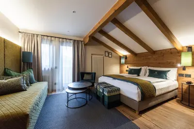 a hotel room with a bed and a couch at Hotel Antares in Selva di Val Gardena