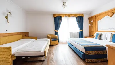 a hotel room with two beds and a window at Hotel Antares in Selva di Val Gardena