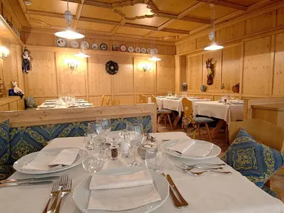 a dining room with tables with white plates and glasses at Hotel Antares in Selva di Val Gardena