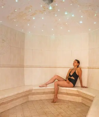 a woman sitting on a bench in a tub at Hotel Antares in Selva di Val Gardena