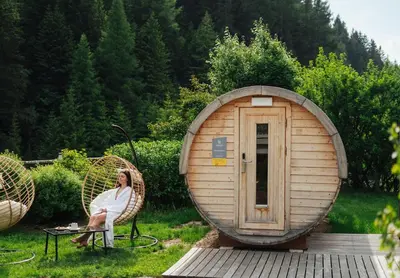 a woman sitting in a chair in front of a round house at Hotel Antares in Selva di Val Gardena