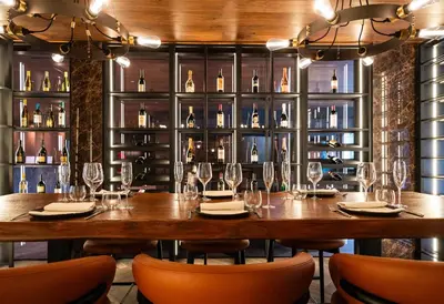 a large wooden table in a room with wine bottles at Hotel Antares in Selva di Val Gardena