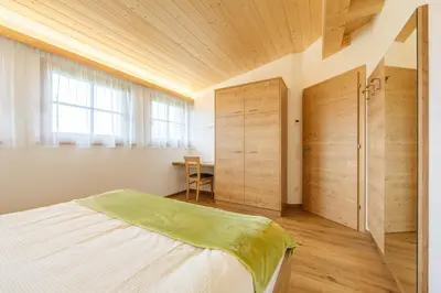 a bedroom with a bed and a wooden ceiling at Krebslechnerhof in Brunico