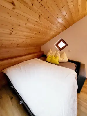 a bed in a room with a wooden ceiling at Krebslechnerhof in Brunico
