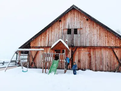 two people standing in front of a barn in the snow at Krebslechnerhof in Brunico