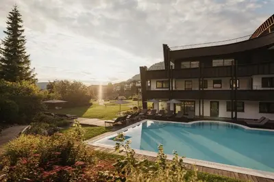 a hotel with a swimming pool in front of a building at Granbaita Dolomites in Selva di Val Gardena