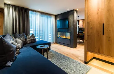 a living room with a blue couch and a fireplace at Granbaita Dolomites in Selva di Val Gardena