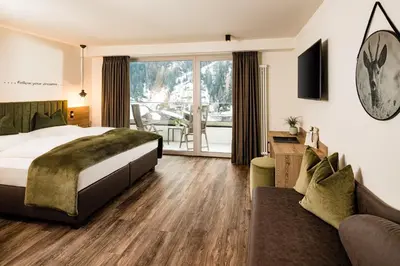 a hotel room with a bed and a couch at Hotel Touring Dolomites in Santa Cristina in Val Gardena