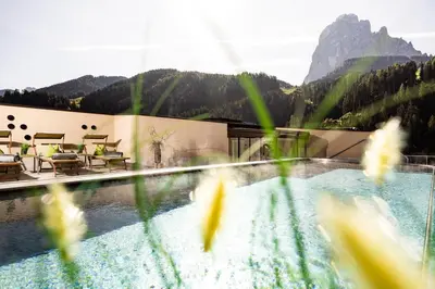 a view of a swimming pool with mountains in the background at Hotel Touring Dolomites in Santa Cristina in Val Gardena