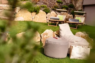 a yard with two chairs and a bench and rocks at Hotel Touring Dolomites in Santa Cristina in Val Gardena