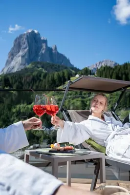 a man and woman holding glasses of red wine at Hotel Touring Dolomites in Santa Cristina in Val Gardena