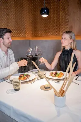a man and woman sitting at a table with wine glasses at Hotel Touring Dolomites in Santa Cristina in Val Gardena