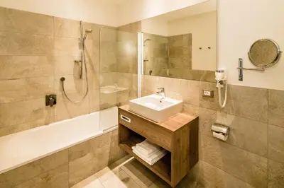 a bathroom with a sink and a shower and a tub at Hotel Touring Dolomites in Santa Cristina in Val Gardena