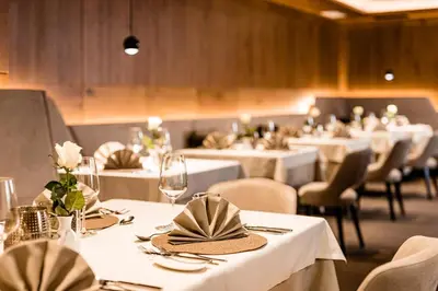 a row of tables with white table cloths and chairs at Hotel Touring Dolomites in Santa Cristina in Val Gardena