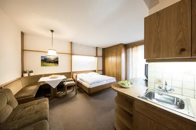 a room with a bed and a kitchen with a sink at Apartments Obermayr in Lana