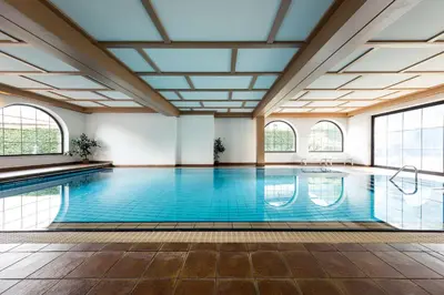 a swimming pool with a large ceiling and windows at Apartments Obermayr in Lana
