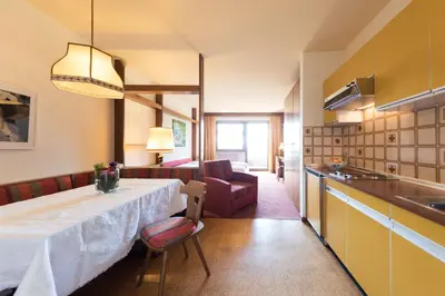 a kitchen and dining room with a table and a couch at Apartments Feyerlin in Lana
