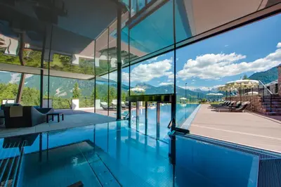 a house with a pool with a view of the mountains at Hotel Albion Mountain Spa Resort Dolomites in Ortisei