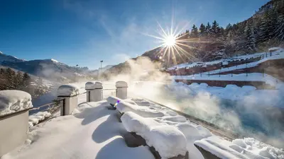 a snow covered train station with the sun in the background at Hotel Albion Mountain Spa Resort Dolomites in Ortisei