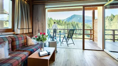 a living room with a couch and a view of a mountain at Hotel Albion Mountain Spa Resort Dolomites in Ortisei