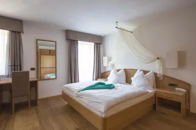 a hotel room with a bed and a desk at Hotel Albion Mountain Spa Resort Dolomites in Ortisei